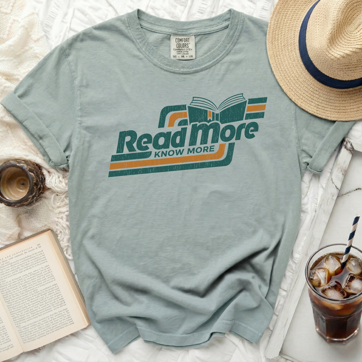 Dusty blue t-shirt with "Read more KNOW MORE" graphic and open book.