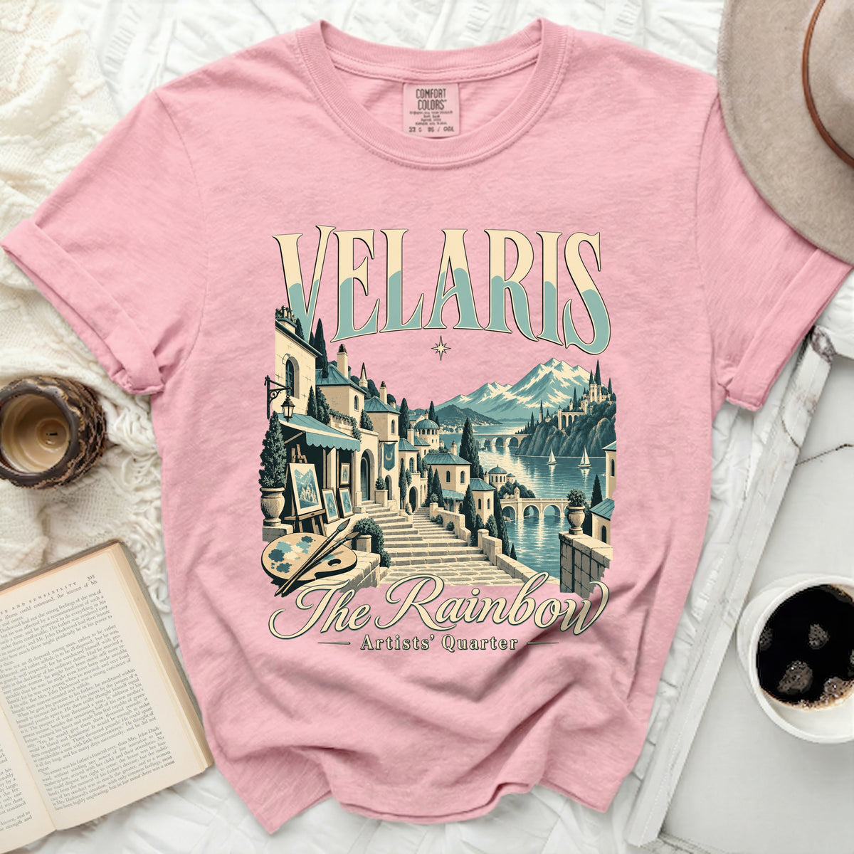 Pink t-shirt with "Velaris The Rainbow Artists' Quarter" graphic art.