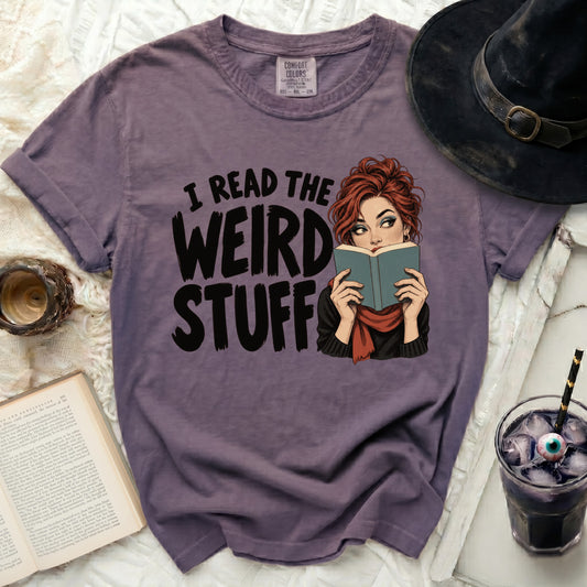 Purple t-shirt with text "I READ THE WEIRD STUFF" and graphic.