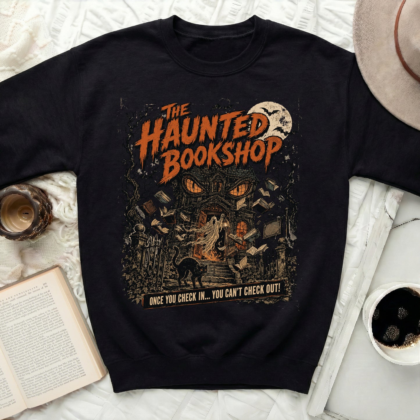 Black sweatshirt with "The Haunted Bookshop" graphic and haunted house scene.