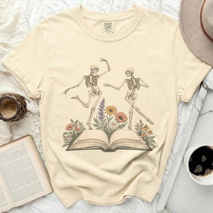 T-shirt with dancing skeletons, open book, and flowers, Comfort Colors tag.