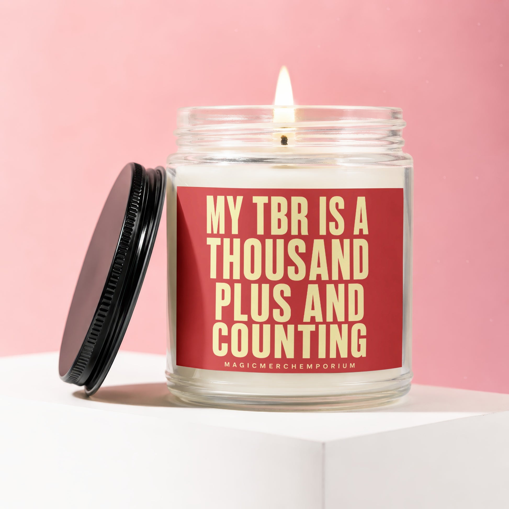 Glass candle with burning wick and black lid, reading "My TBR is a thousand plus and counting".