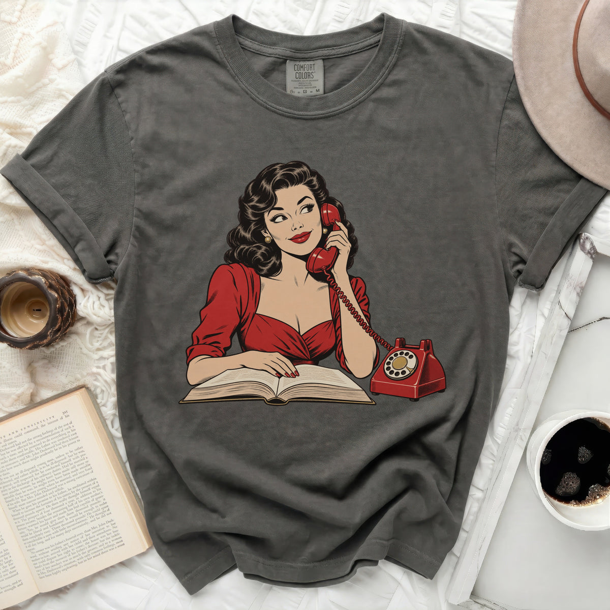 Graphic tee with a vintage comic-style woman talking on a red phone next to a book.
