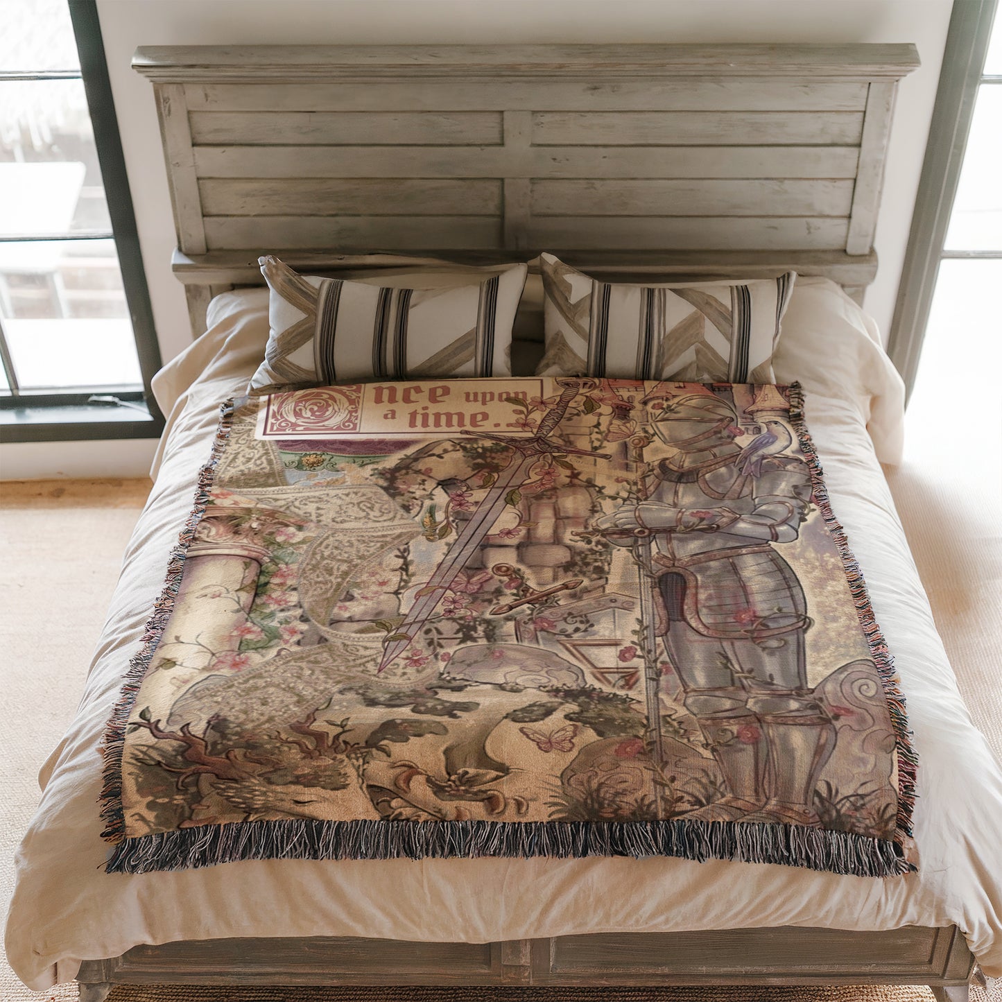 a bed with a decorative blanket that has a medieval-style illustration on it. The blanket is placed on a wooden headboard, and there are pillows on the bed.