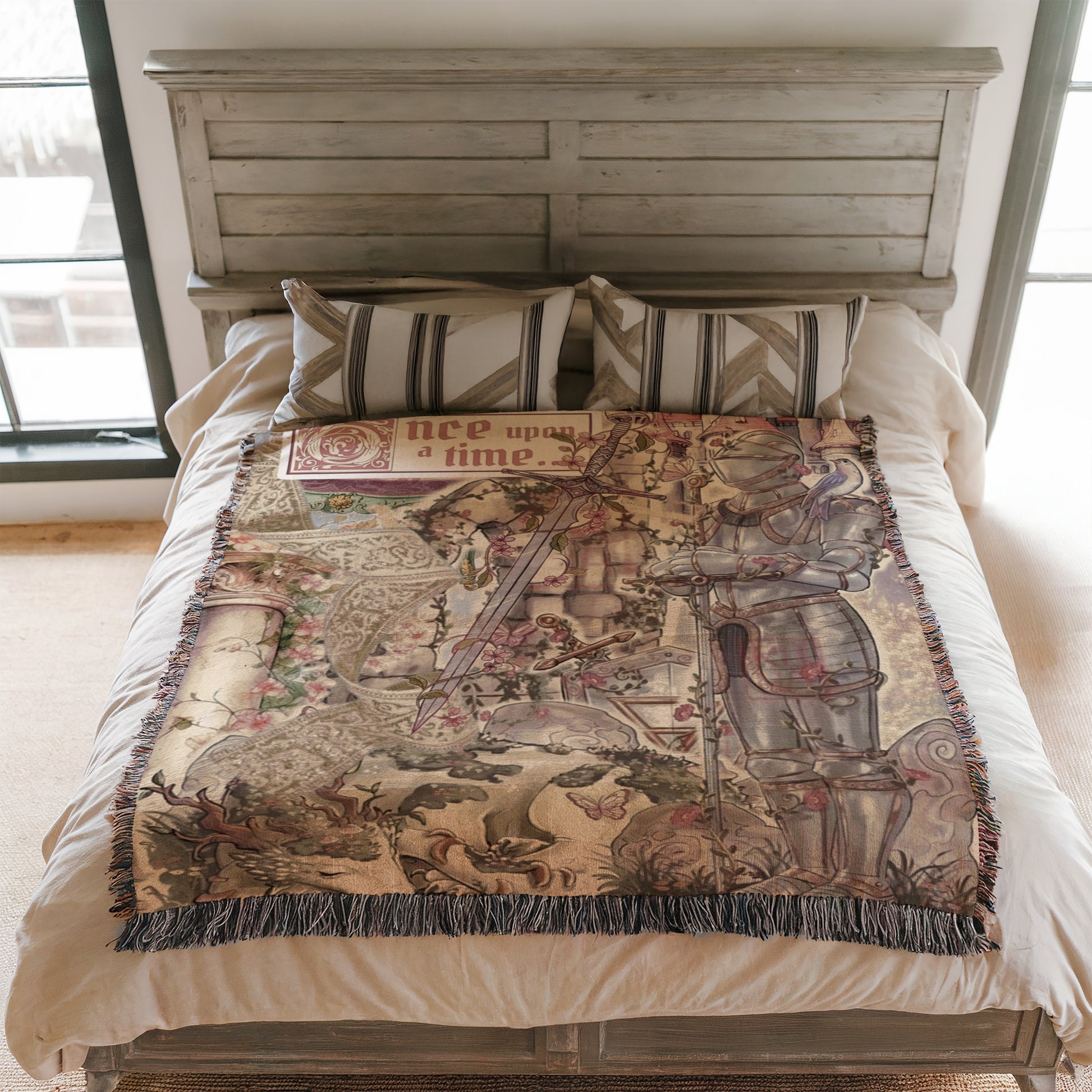 a bed with a decorative blanket that has a medieval-style illustration on it. The blanket is placed on a wooden headboard, and there are pillows on the bed.
