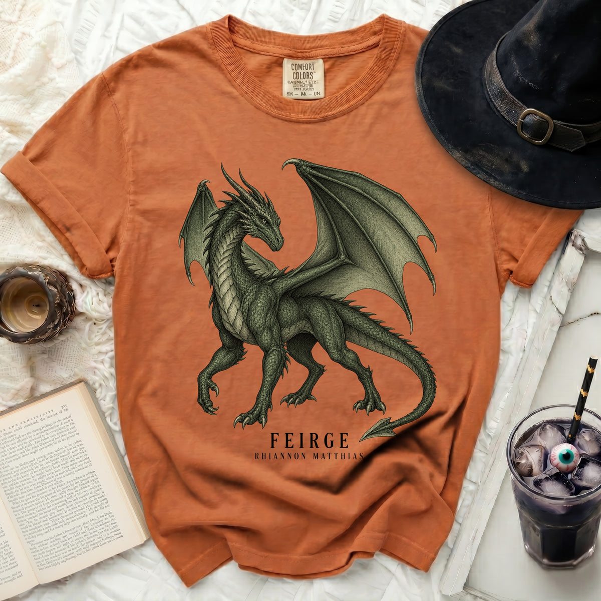 Orange t-shirt with a green dragon graphic and text "FEIRGE RHIANNON MATTHIAS".