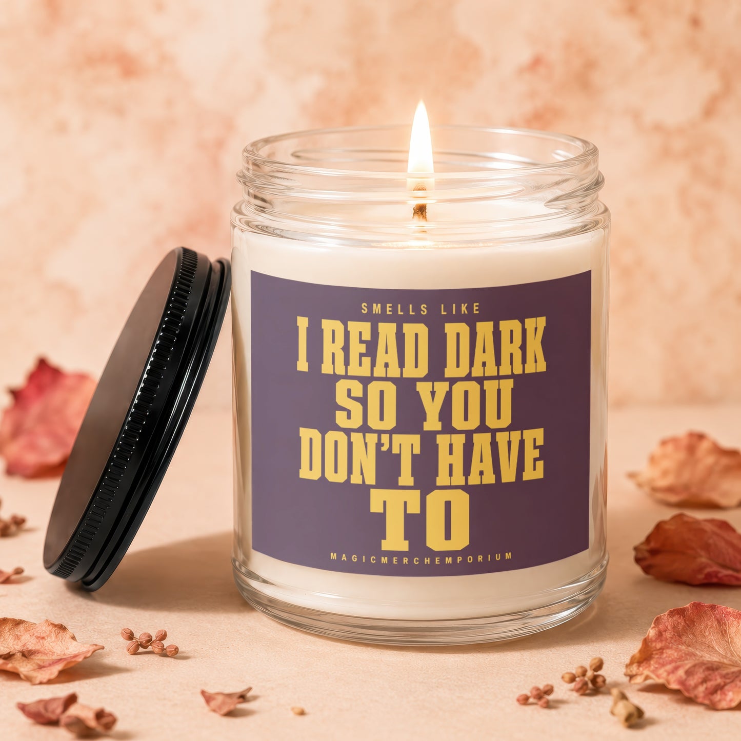 Lit candle in a glass jar with a purple label reading "Smells like I read dark so you don't have to".
