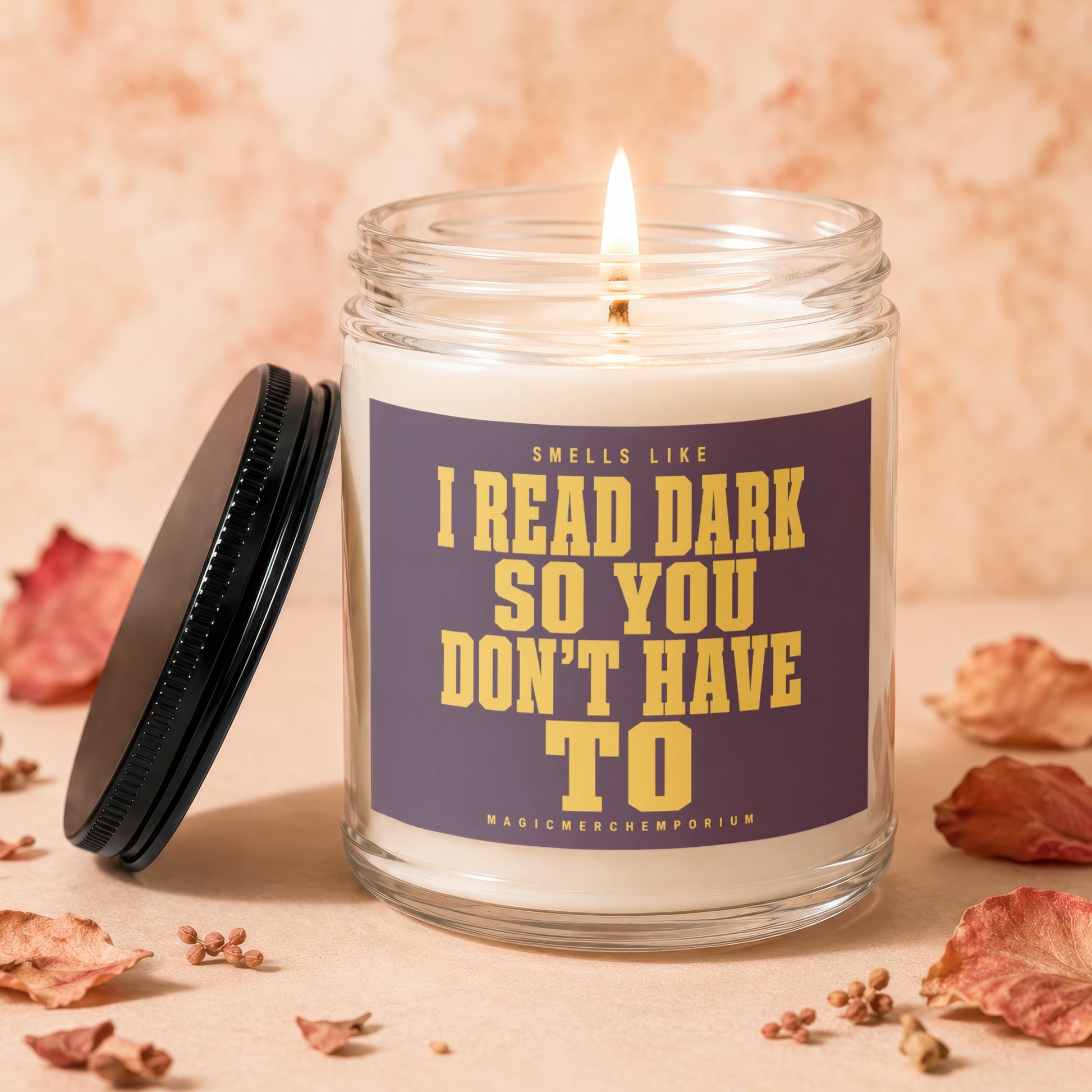 Lit candle in a glass jar with a purple label reading "Smells like I read dark so you don't have to".