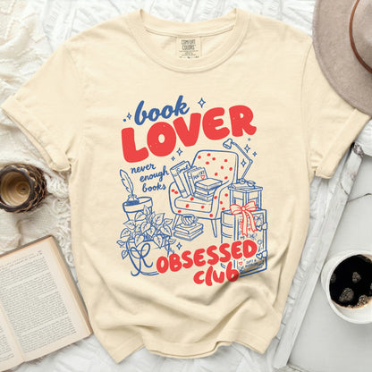 Beige Comfort Colors t-shirt with "Book Lover never enough books Obsessed Club" graphic.