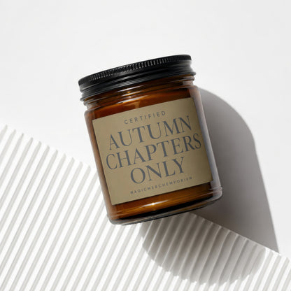 Amber glass candle with black lid and "Autumn Chapters Only" label.