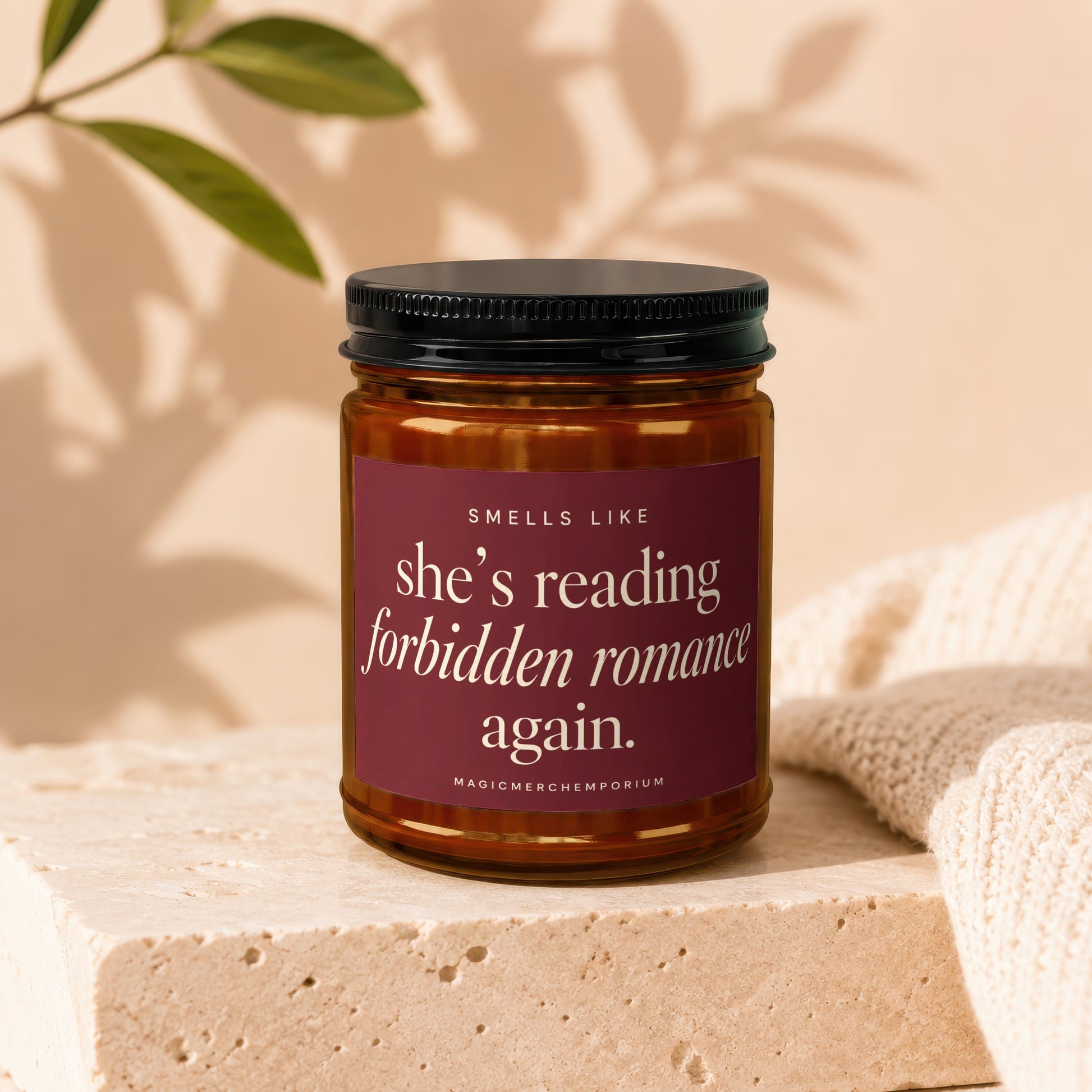 Amber candle with a dark label reading "She's reading forbidden romance again."