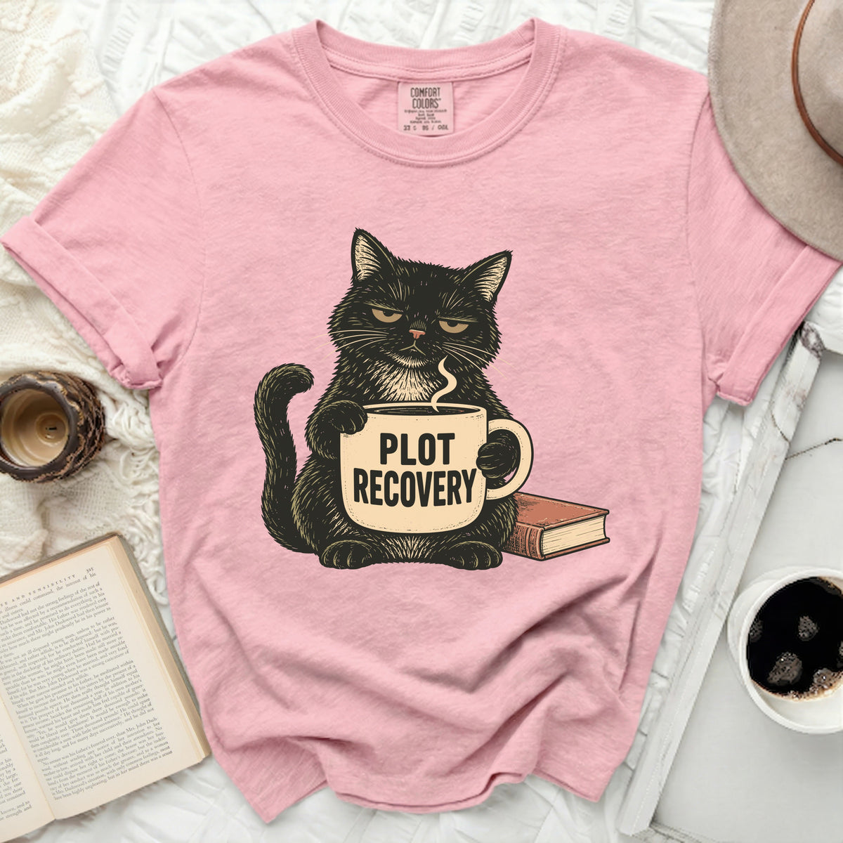 Pink t-shirt with black cat holding "PLOT RECOVERY" mug and a book.