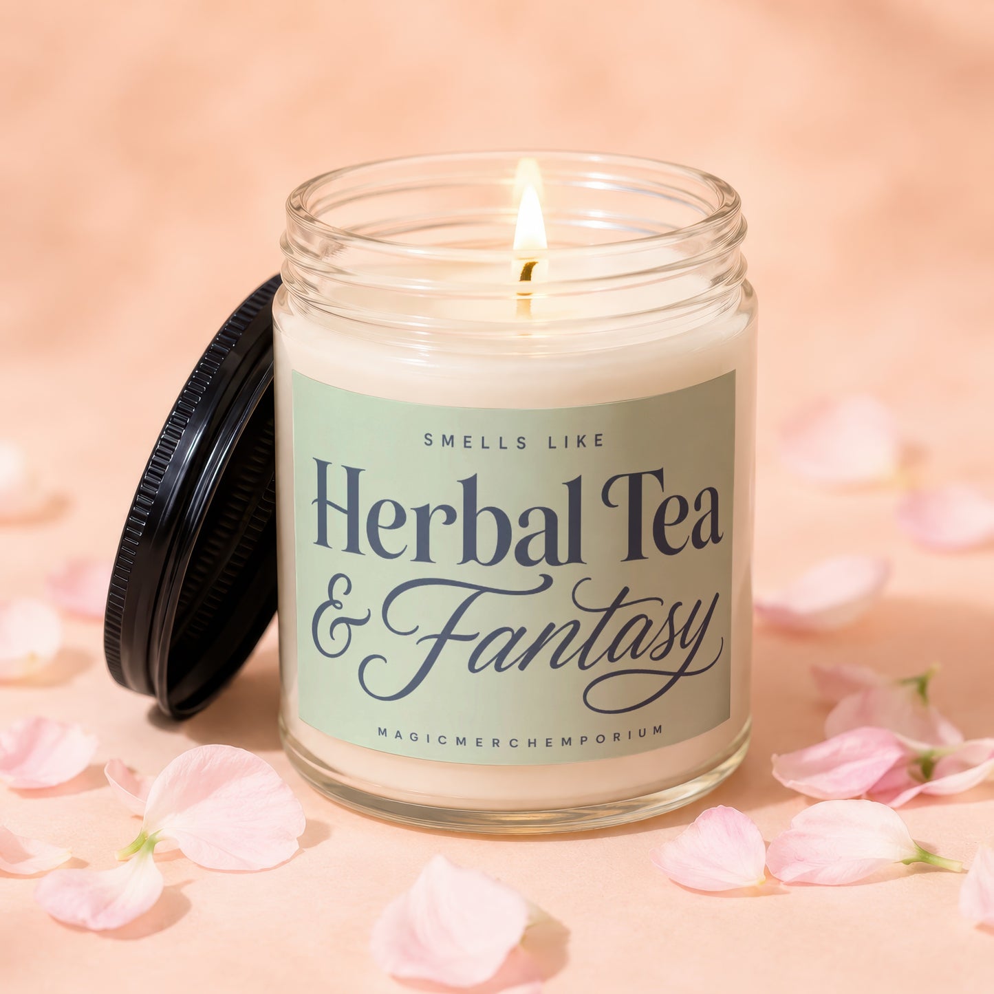 Lit glass candle with black lid, reads "Smells Like Herbal Tea & Fantasy" and "MagicMerchEmporium."