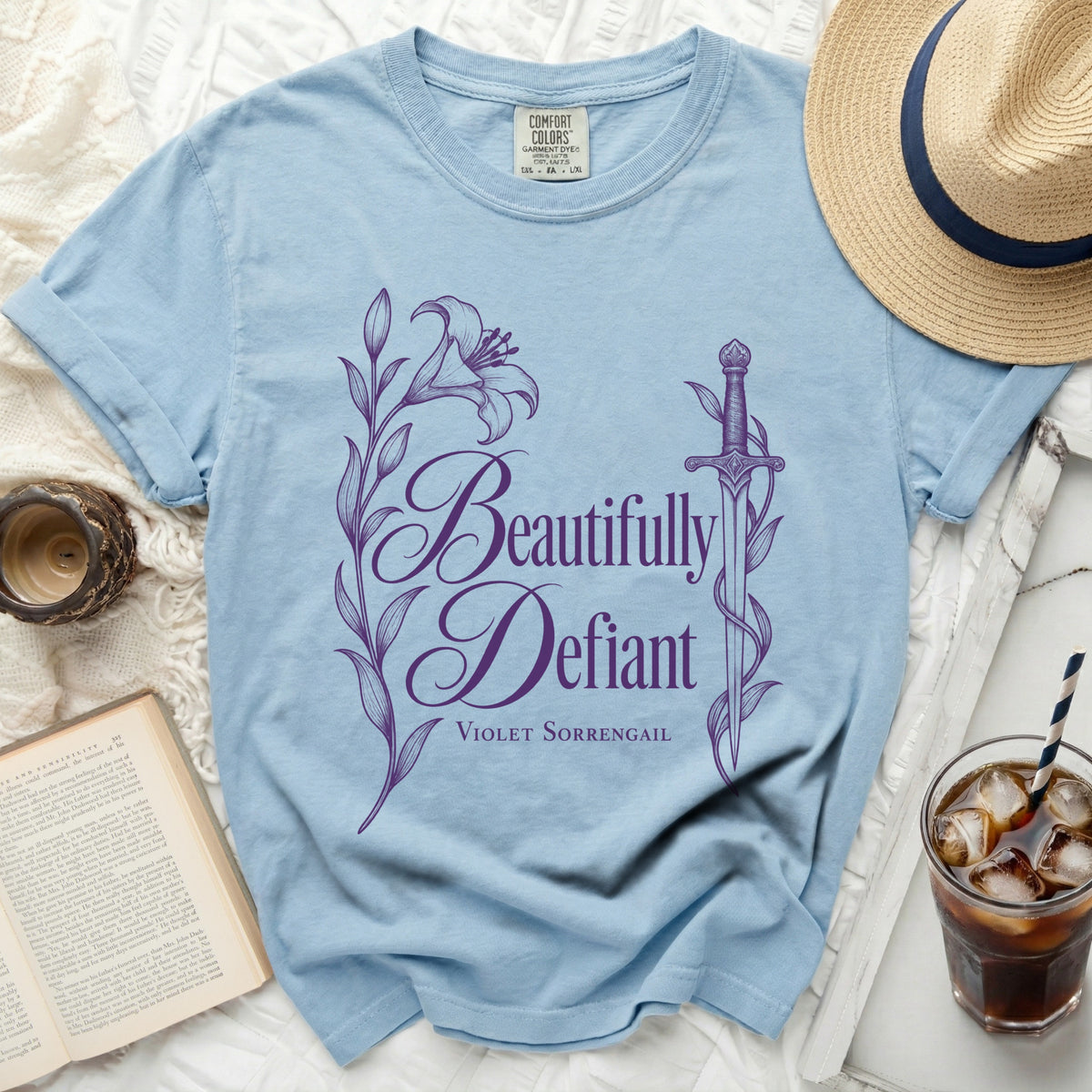 Light blue t-shirt with purple "Beautifully Defiant Violet Sorrengail" text and floral design.