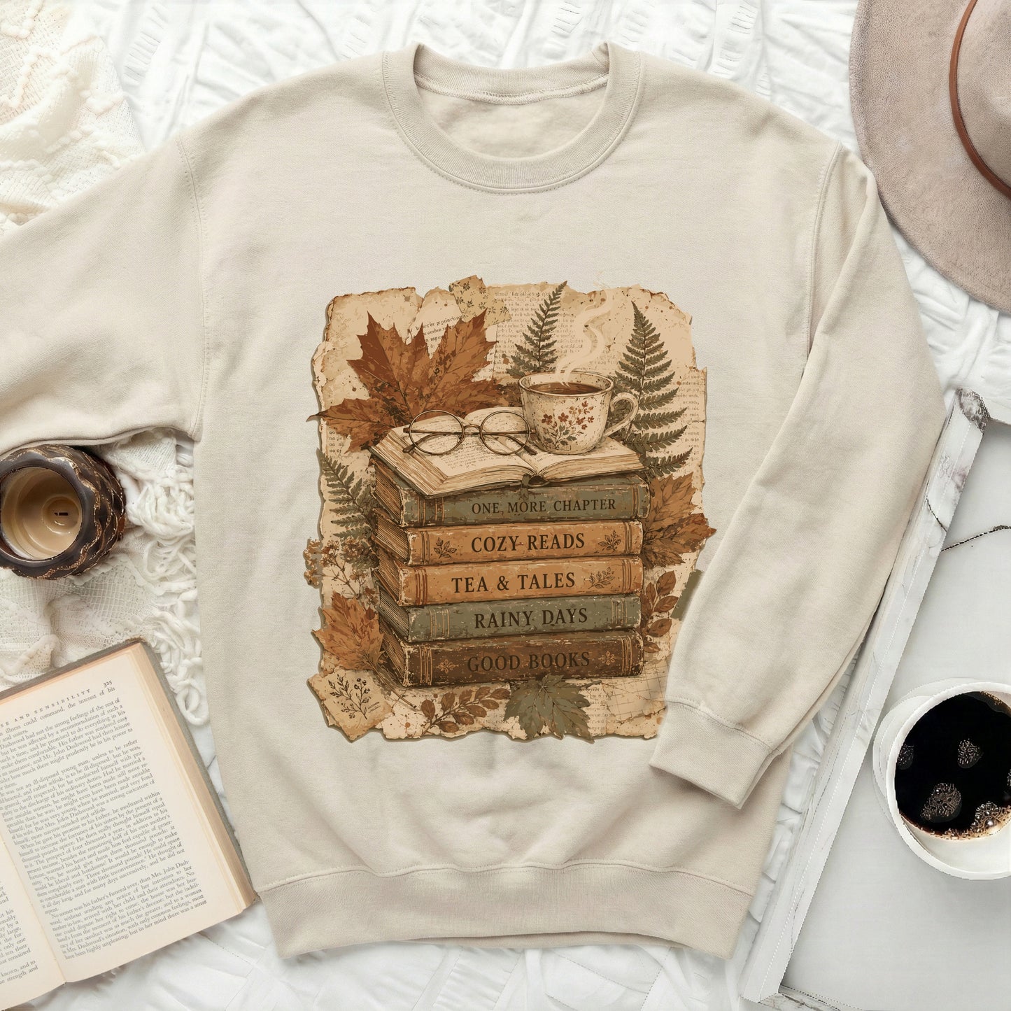 Cream sweatshirt with a vintage book stack graphic and autumn leaves.