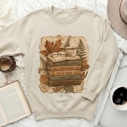 Cream sweatshirt with a vintage book stack graphic and autumn leaves.
