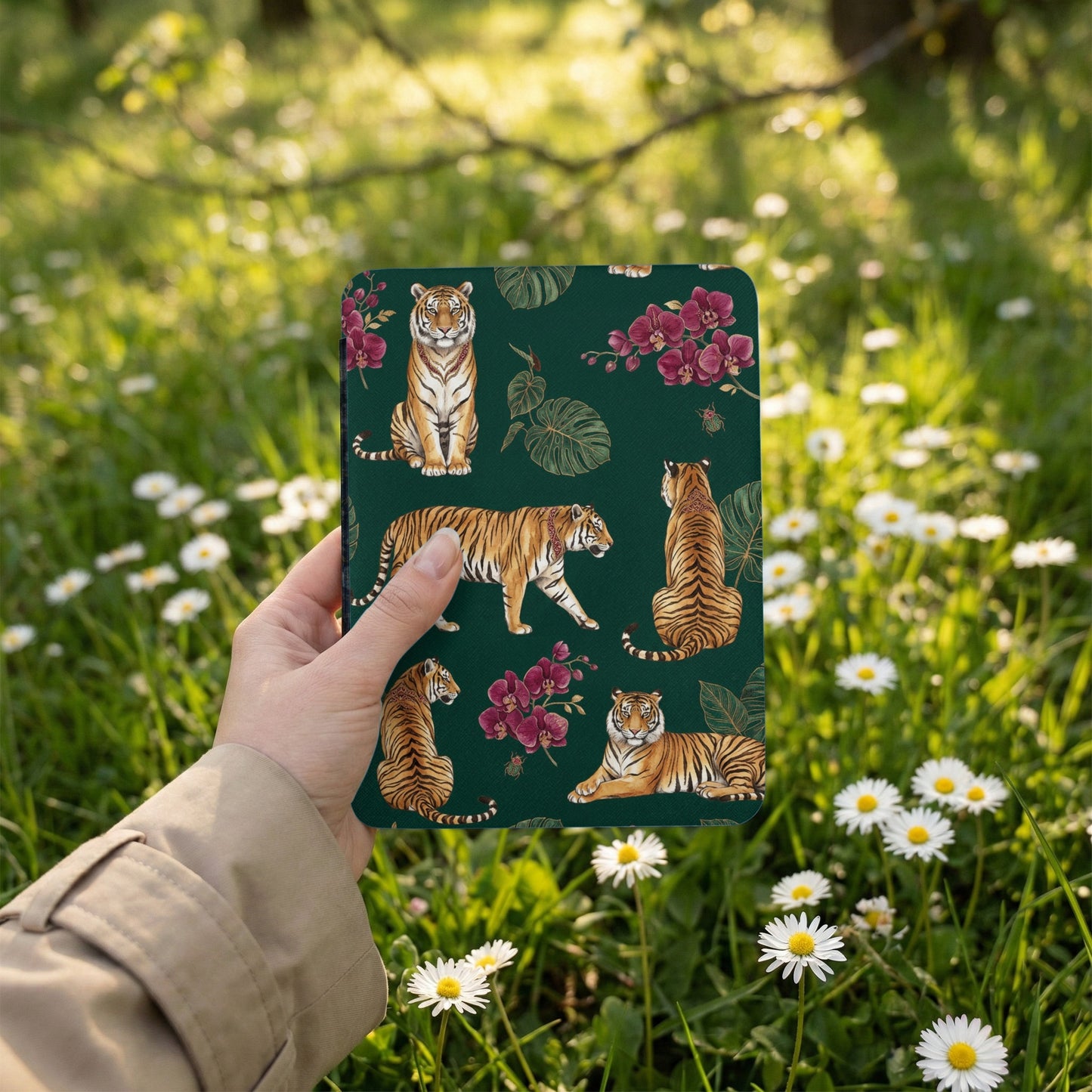 Dark green cover featuring a tiger and orchid pattern, held in a hand outdoors.