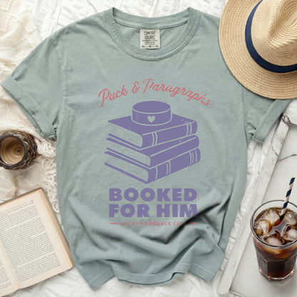 Light blue t-shirt with stacked books and "Puck & Paragraphs Booked For Him" text.