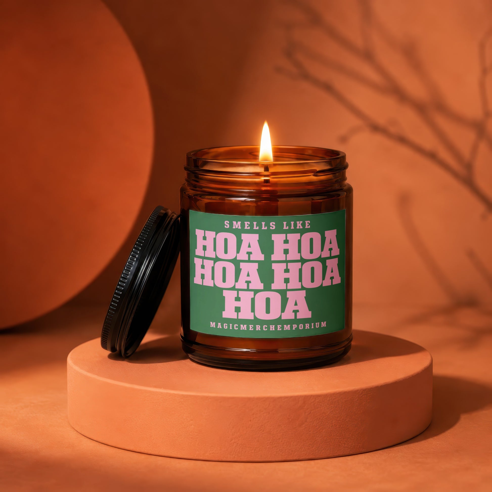 Amber candle with lit wick and a green label that reads "Smells Like Hoa Hoa Hoa Hoa"