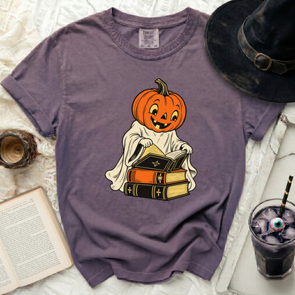Purple t-shirt with cartoon pumpkin ghost reading books and witch hat.