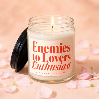 Lit candle with "Enemies to Lovers Enthusiast" label surrounded by pink flower petals.