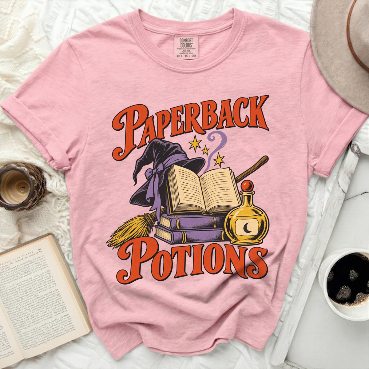 Pink t-shirt with "Paperback Potions" graphic featuring a witch hat, book, and potion bottle.
