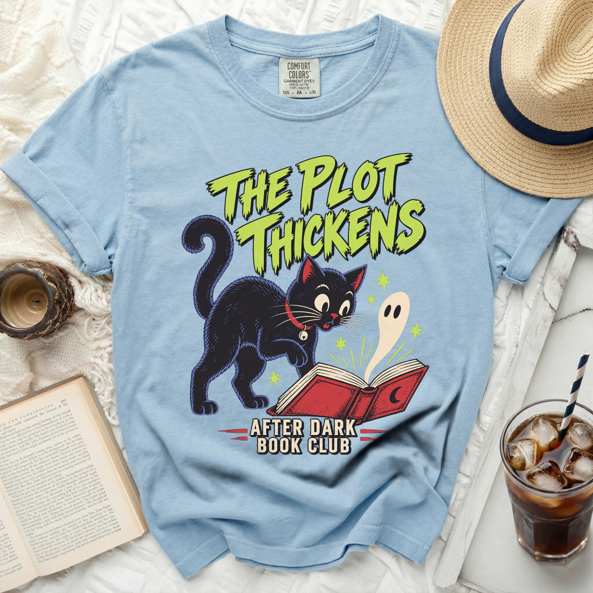 Blue t-shirt with black cat, ghost, and book graphic, "The Plot Thickens" text.