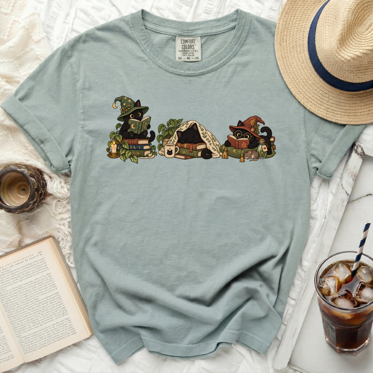 Three black cats in wizard hats read books on a t-shirt.