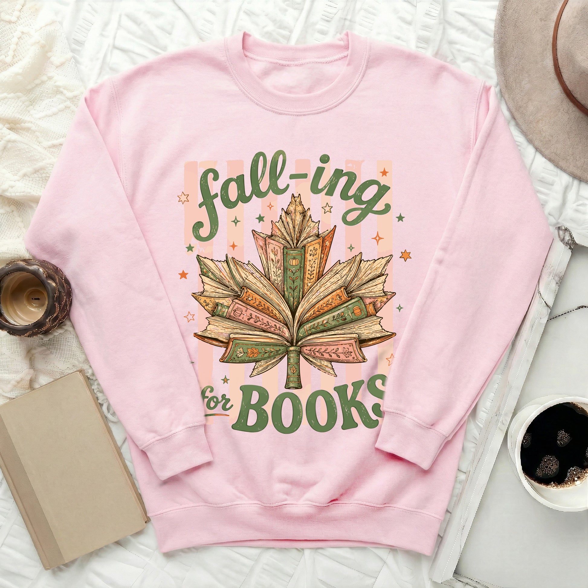 Pink sweatshirt with "fall-ing for BOOKS" text over a maple leaf made of books.