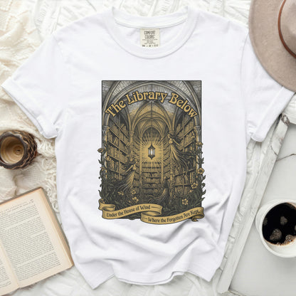 White t-shirt with "The Library Below - Under the House of Wind - Where the Forgotten Are Kept" graphic.