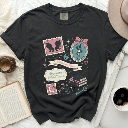 Black t-shirt with "Spymaster Night Court" text and book, sword, and stamp graphics.