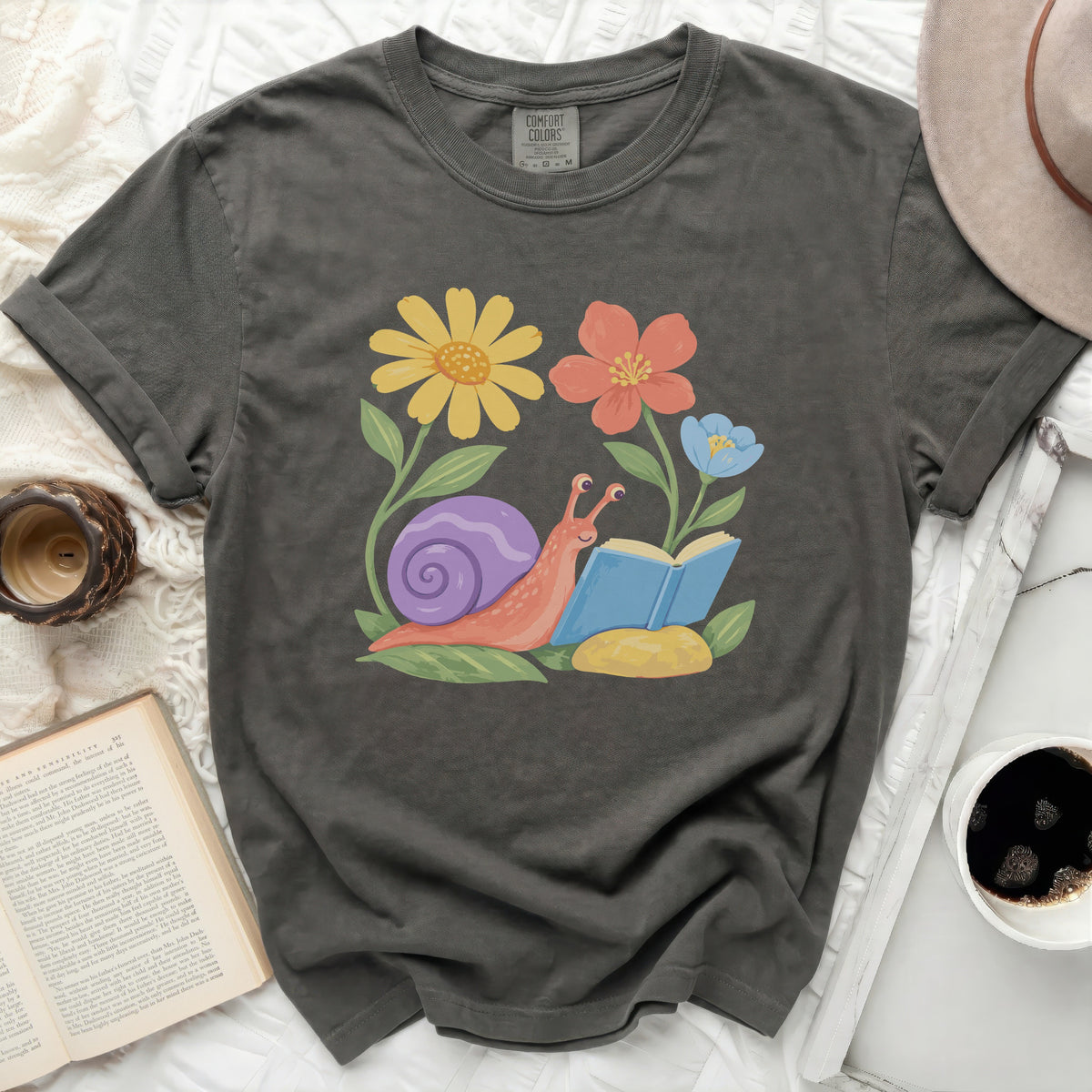 Grey t-shirt with a graphic of a snail reading a book among flowers.