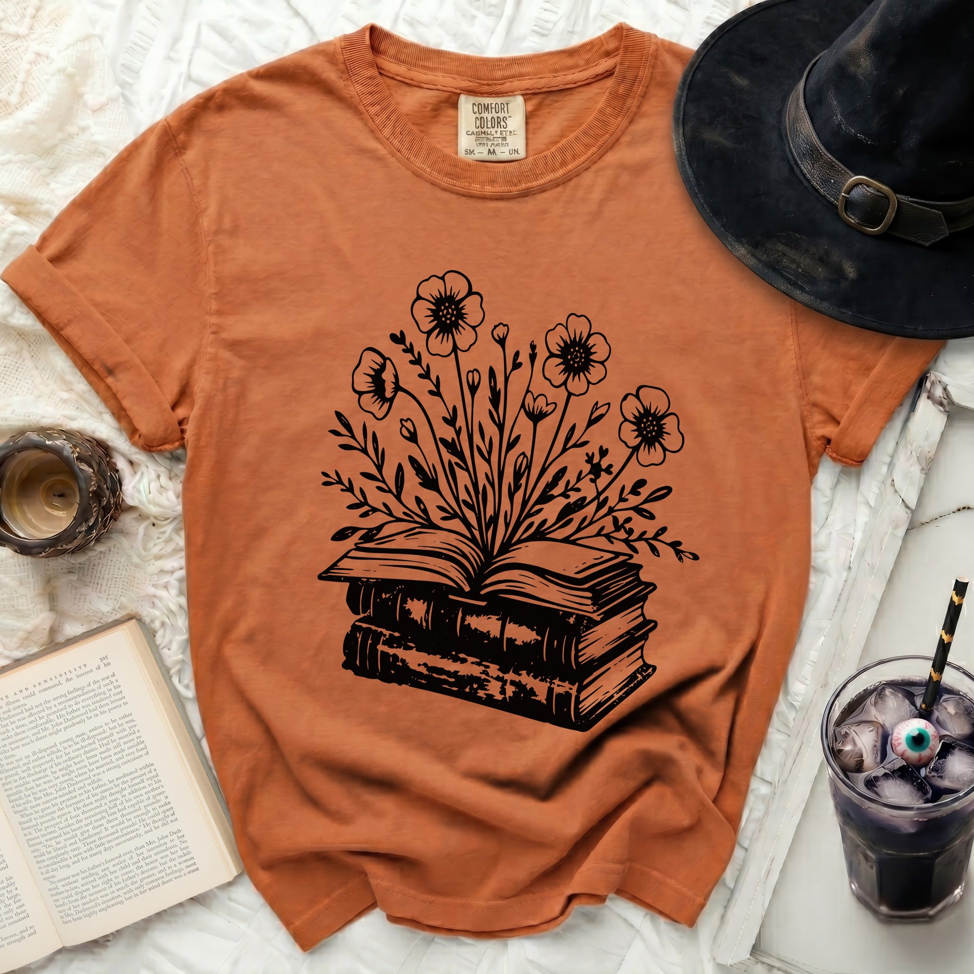 Orange t-shirt with a black graphic of an open book blooming with flowers.