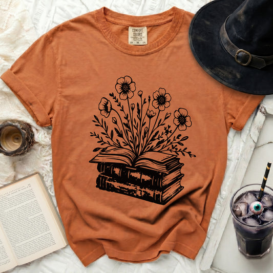 Orange t-shirt with a black graphic of an open book blooming with flowers.