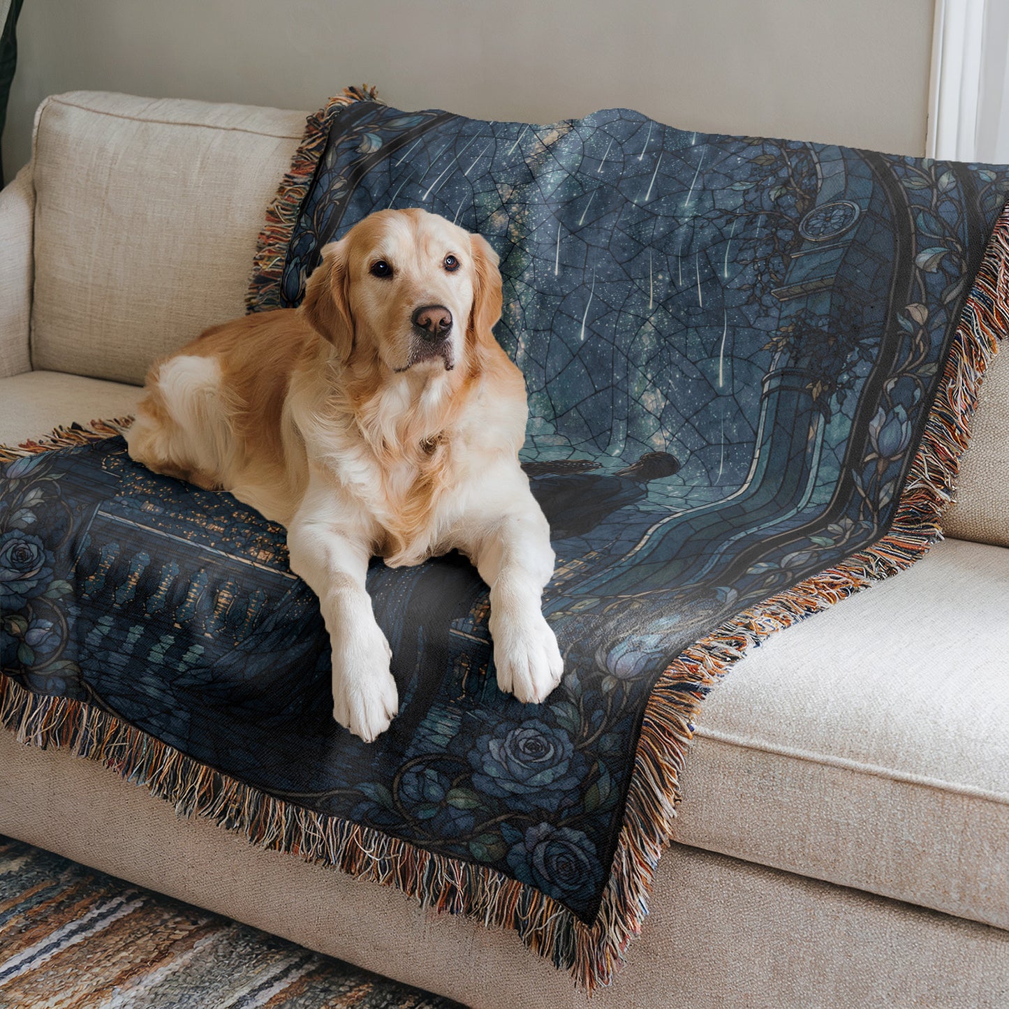 A golden retriever dog is sitting on a blue and black patterned blanket on a beige couch.