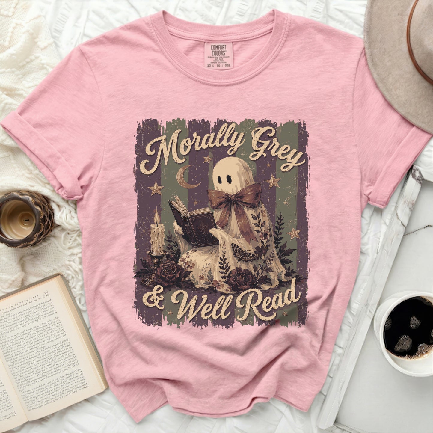 Pink t-shirt with graphic of a ghost reading a book, titled "Morally Grey & Well Read".