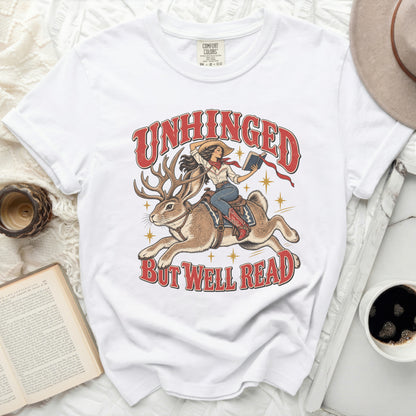 White t-shirt with graphic of woman riding rabbit with antlers, reading a book.