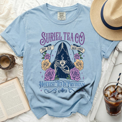 Light blue t-shirt with Suriel Tea Co. design featuring a skeleton in a cloak holding tea.