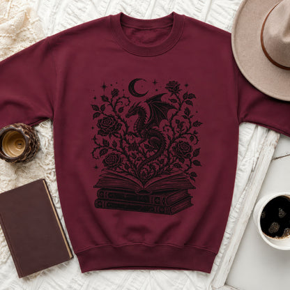 Maroon sweatshirt with black dragon, roses, moon, and stars design on open books.