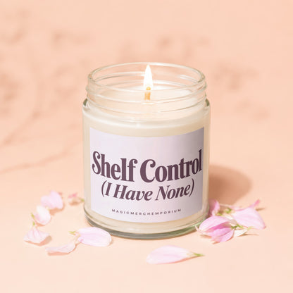 Glass jar candle with lit wick, label reads "Shelf Control (I Have None)".