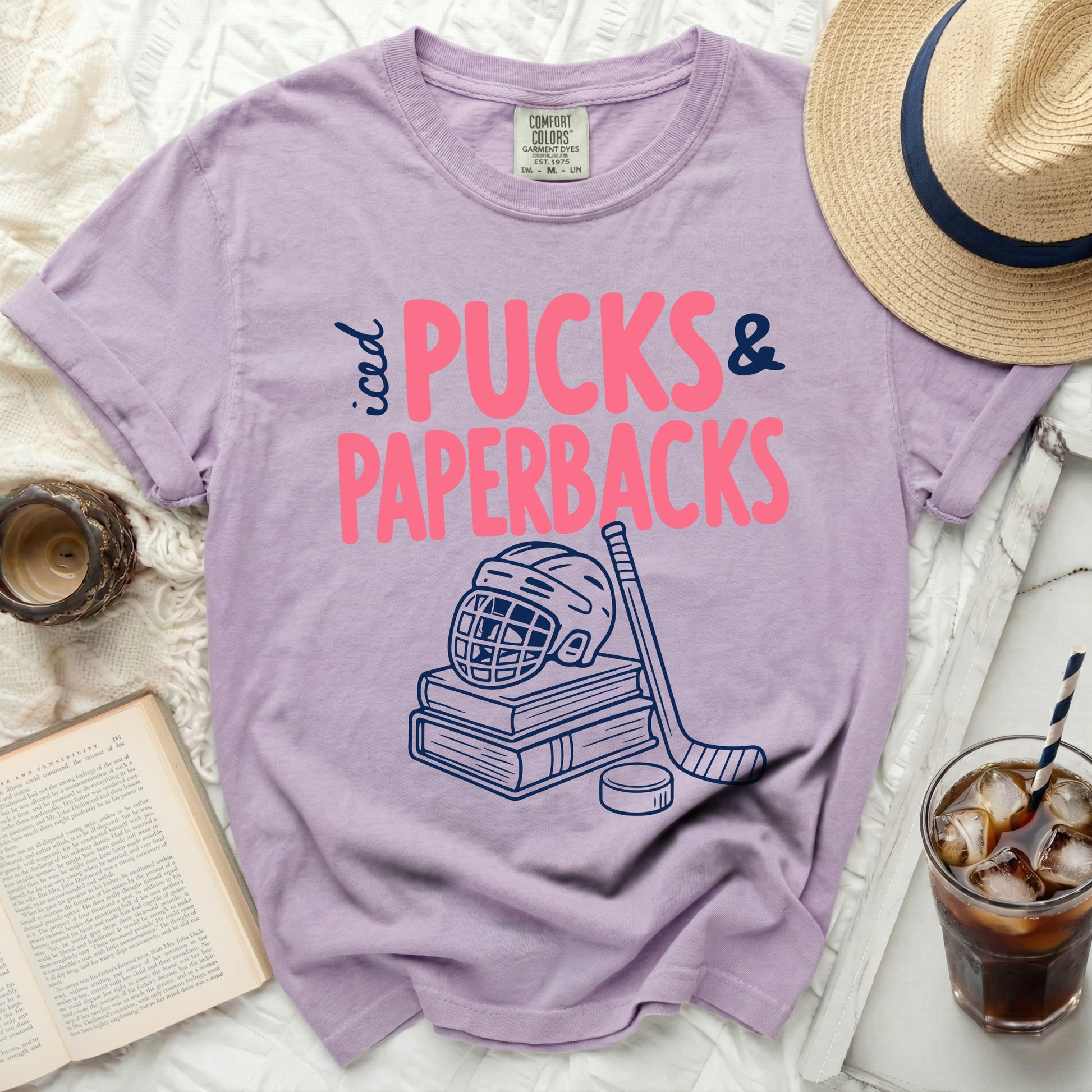 Purple t-shirt with "iced PUCKS & PAPERBACKS" and hockey gear.