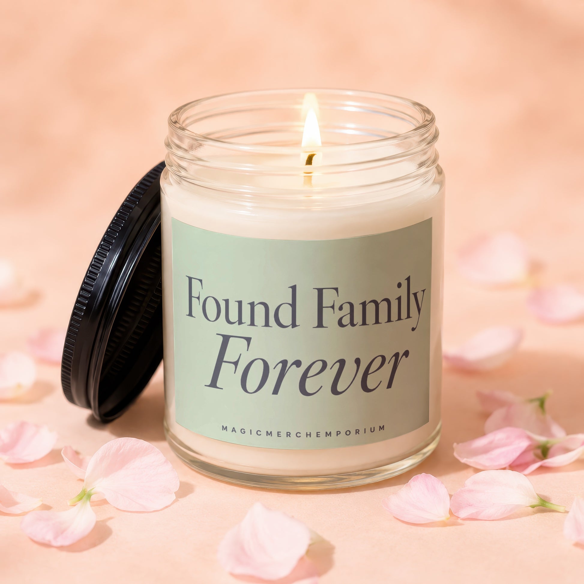 Glass candle with lit wick, label reads "Found Family Forever"
