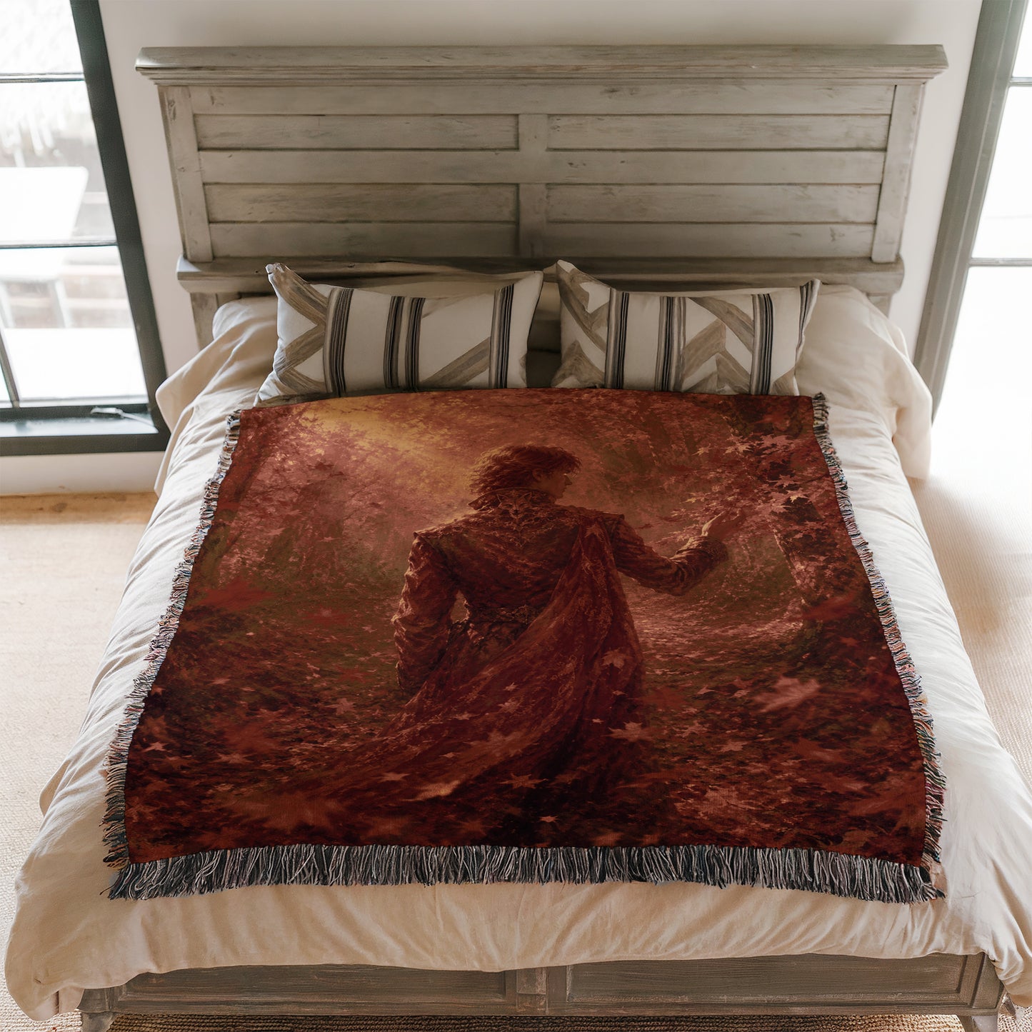a bedroom with a bed covered in a red and brown blanket featuring a painting of a woman. The bed is positioned against a white wooden headboard, and there are two pillows on the bed.