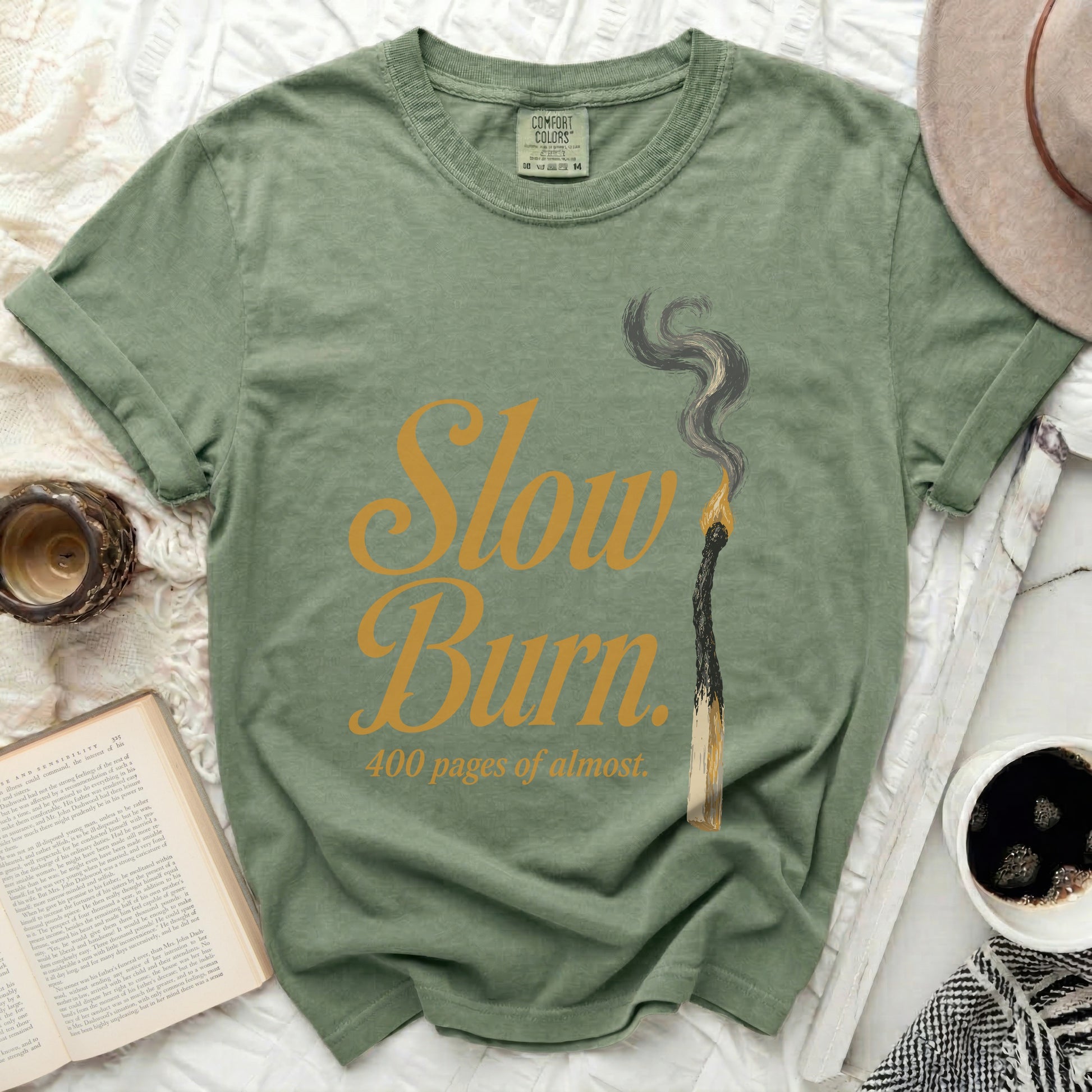Green t-shirt with "Slow Burn 400 pages of almost" text and burnt match graphic.