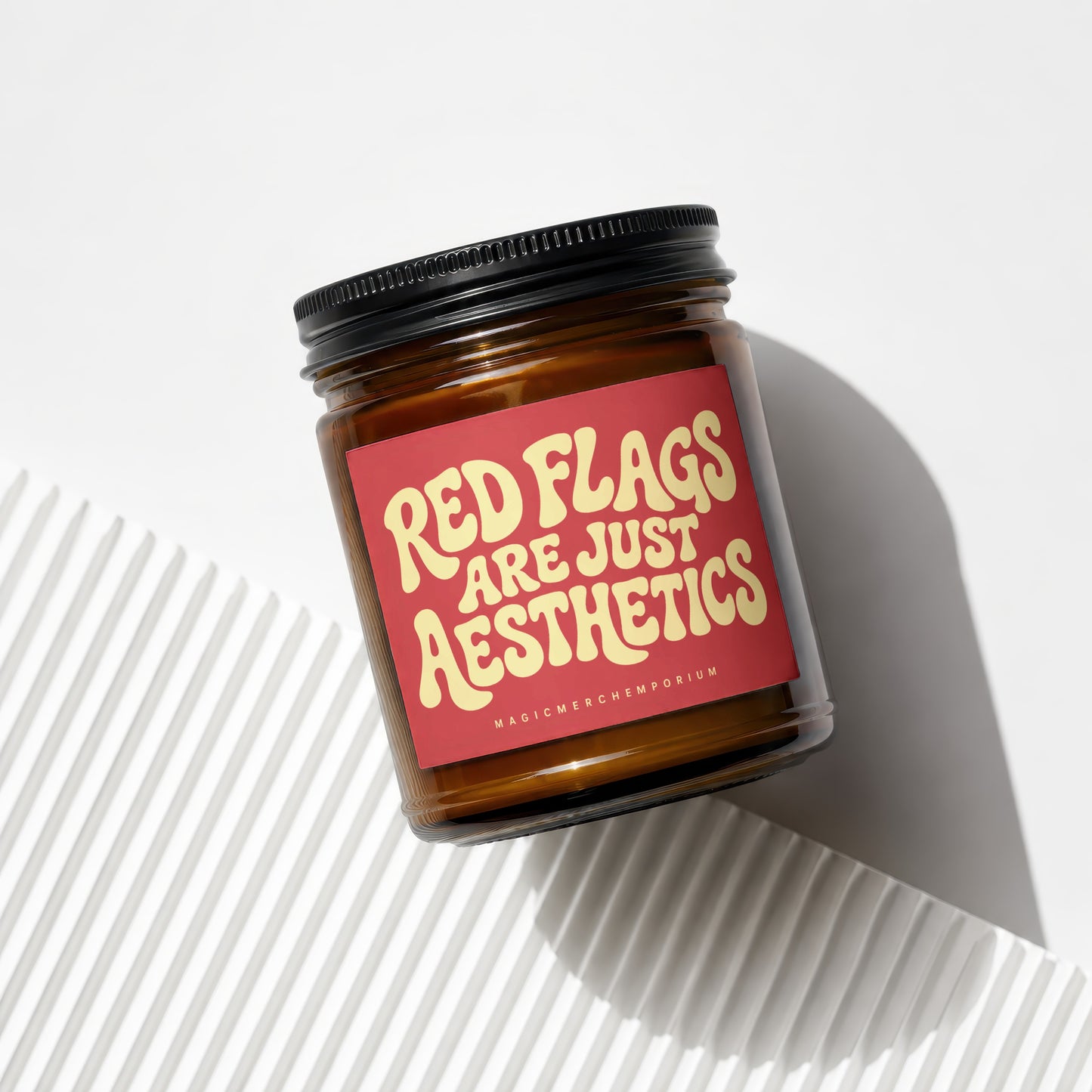 Amber glass candle with red label reading "RED FLAGS ARE JUST AESTHETICS".