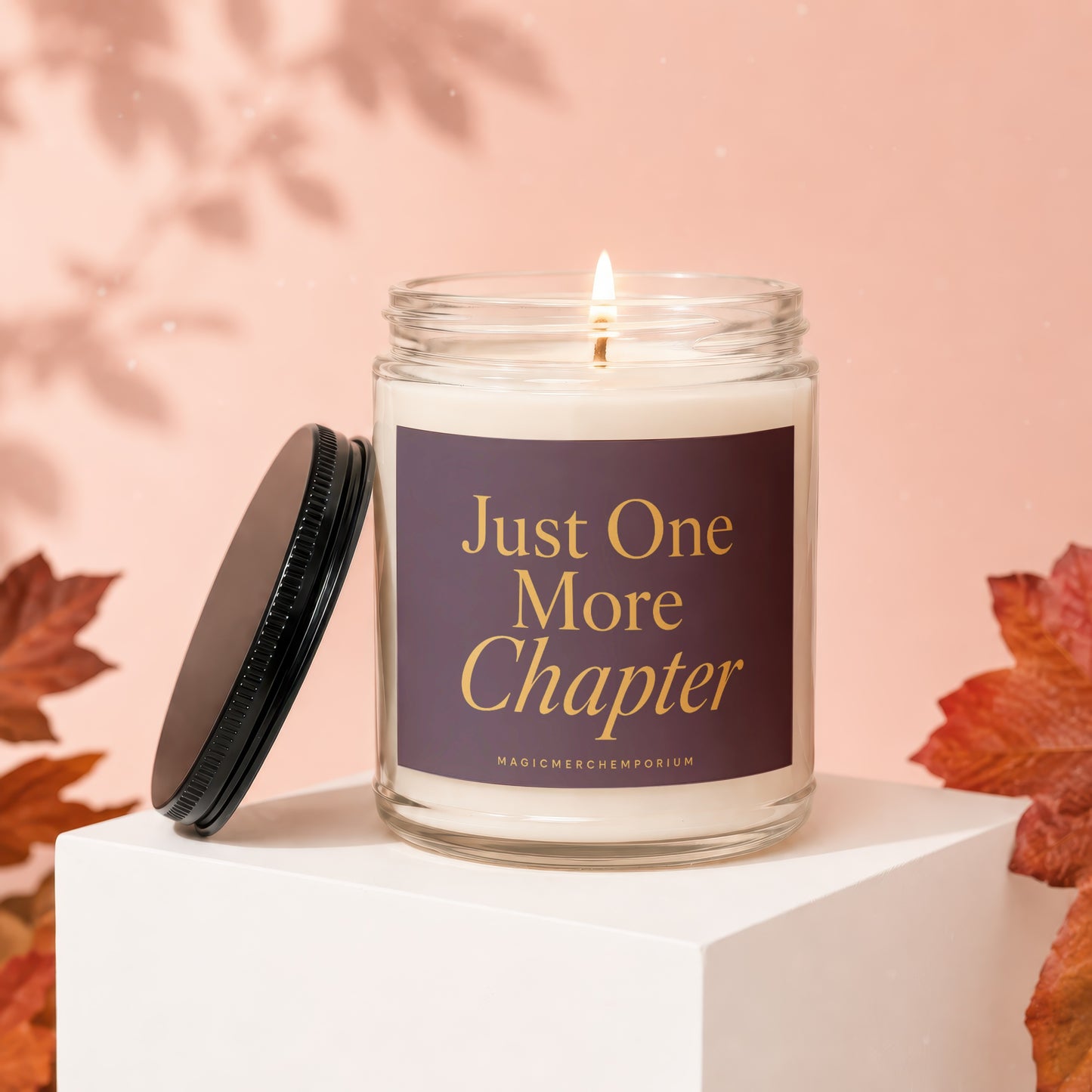 Glass candle with purple label reading "Just One More Chapter".