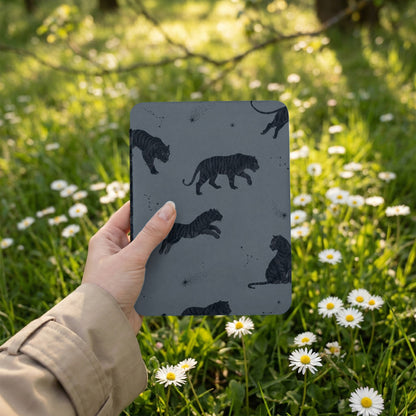 Dark gray object with black tiger pattern and constellations held by a hand in a tan jacket.