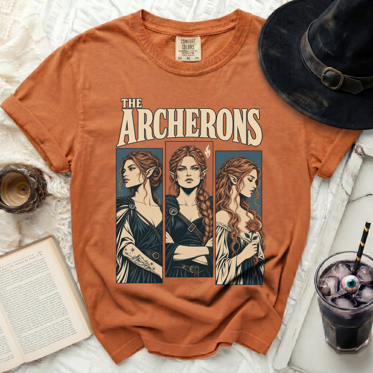 Orange t-shirt with "The Archerons" text and three illustrated elf-like women.