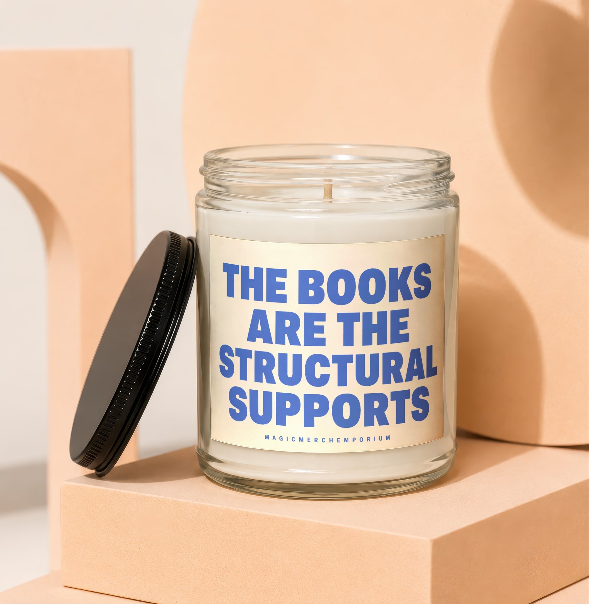Glass candle with lid removed, label reads "The Books Are The Structural Supports."
