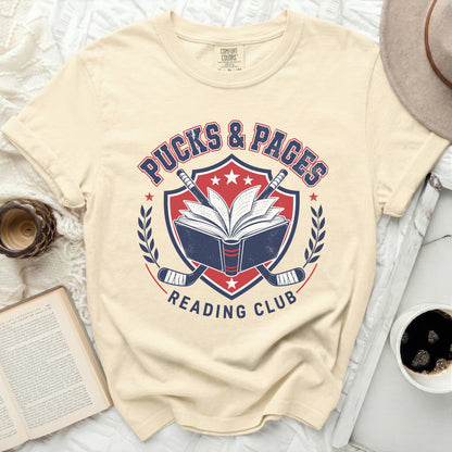 Cream t-shirt with "Pucks & Pages Reading Club" text and hockey imagery.
